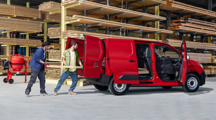 Homens a carregar madeira numa Citroën Berlingo Van vermelha