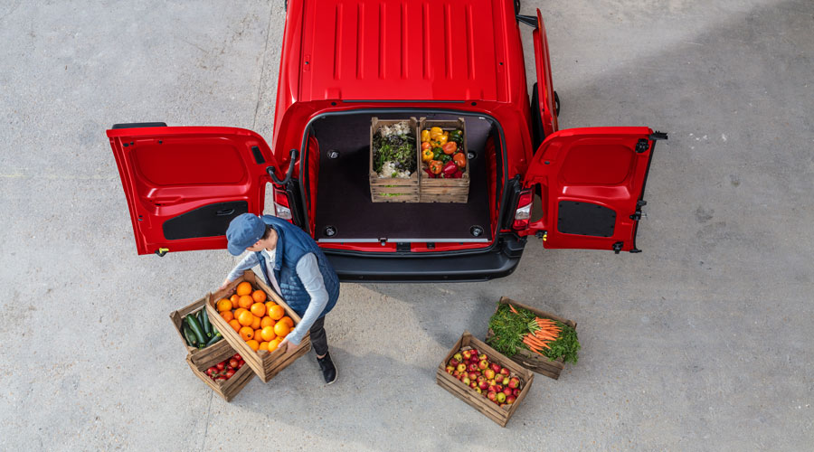 Homem a carregar caixas de fruta numa Citroën Berlingo Van vermelha