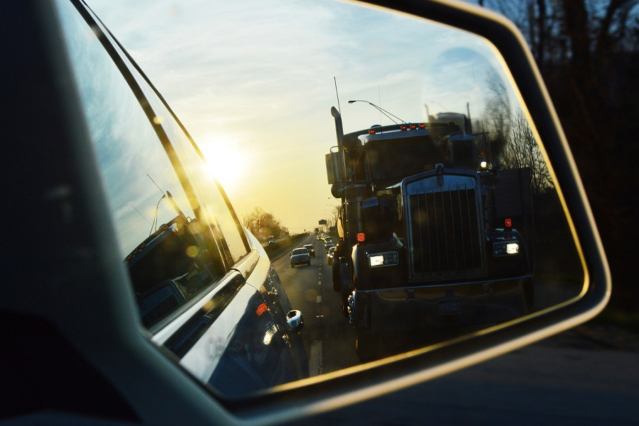 Espelho lateral de um carro refletindo os veículos na estrada